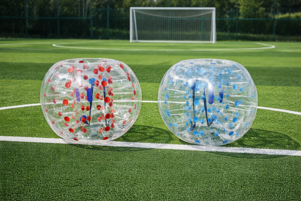 Joueurs équipés de bulles gonflables transparentes pratiquant le bubble foot sur pelouse lors d’une animation sportive en extérieur.
