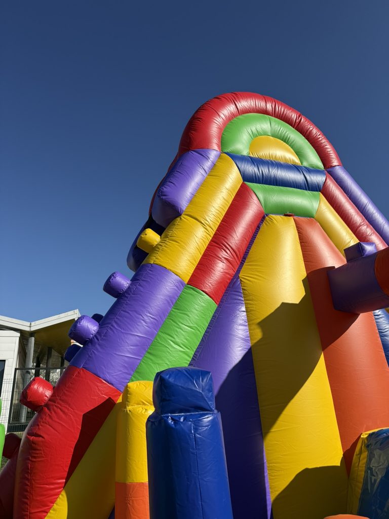 Grande structure gonflable LEGO avec toboggan haut offrant une descente impressionnante pour enfants