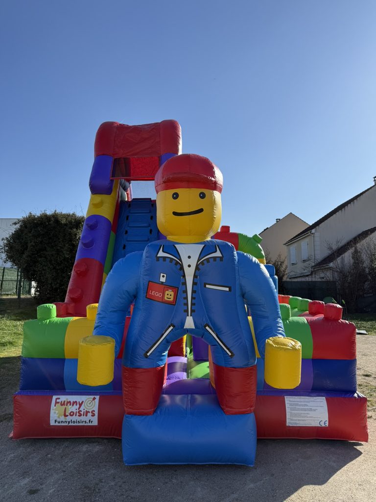 Entrée d’une structure gonflable LEGO avec une grande figurine LEGO géante attirant les enfants