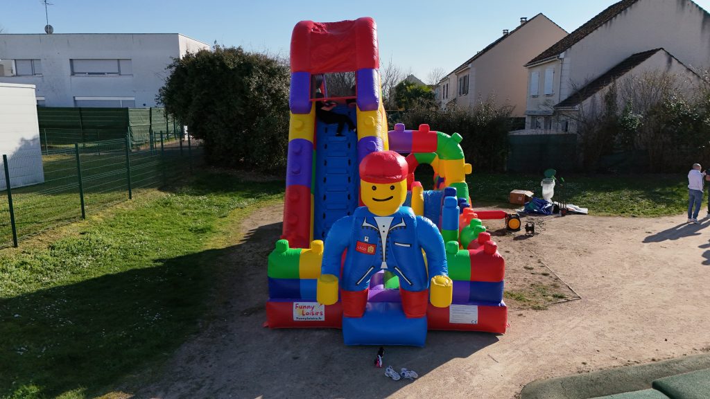 Groupe d’enfants jouant ensemble sur une structure gonflable LEGO lors d’une fête d’anniversaire