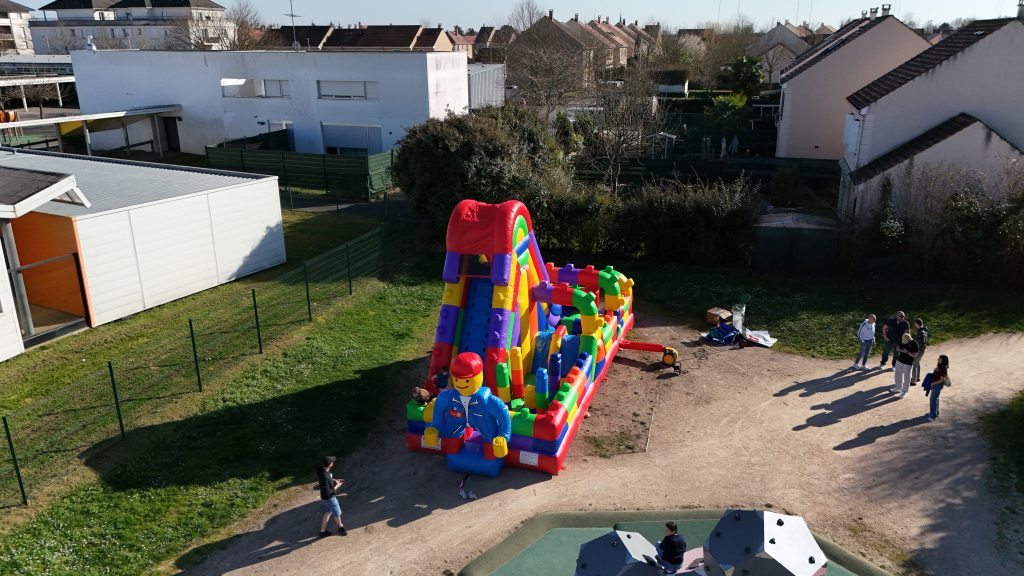 Détail d’une structure gonflable LEGO colorée avec briques géantes pour enfants lors d’une animation