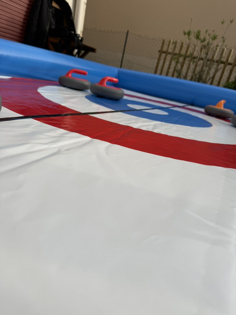 Joueur lançant une pierre sur un curling gonflable en visant la cible lors d’un jeu