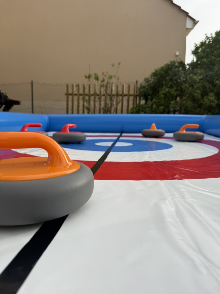 Groupe de joueurs autour d’un curling gonflable lors d’une animation conviviale en extérieur