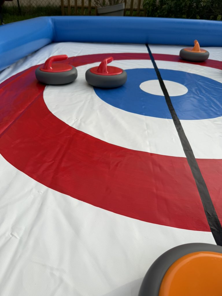 Plusieurs pierres sur une piste de curling gonflable proches de la cible pendant une partie