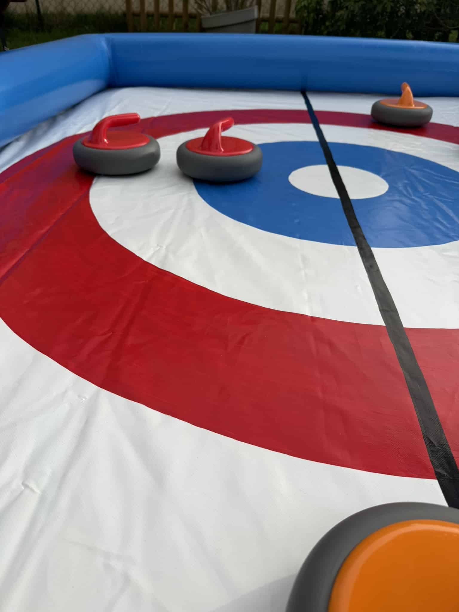 Cible du curling gonflable rouge et bleue avec palets