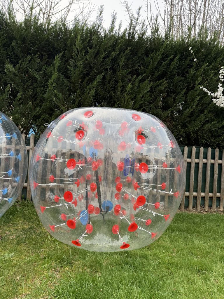 Joueurs allongés au sol en train de rire après une chute en Bubble Foot lors d’une activité en extérieur